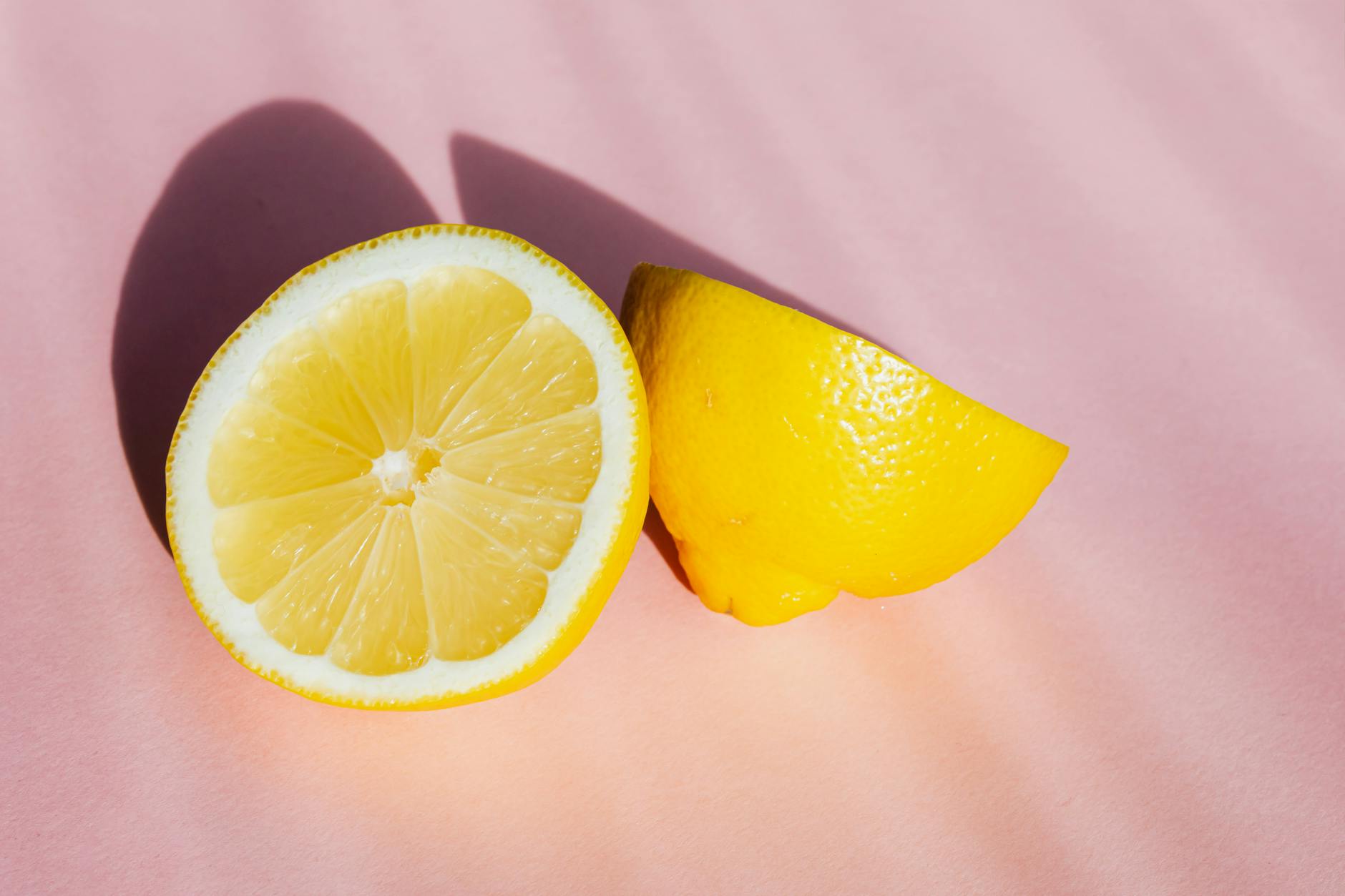 Two halves of a fresh lemon on a pink background, symbolizing the gentle, citrus-inspired design of lemon clitoral vibrators