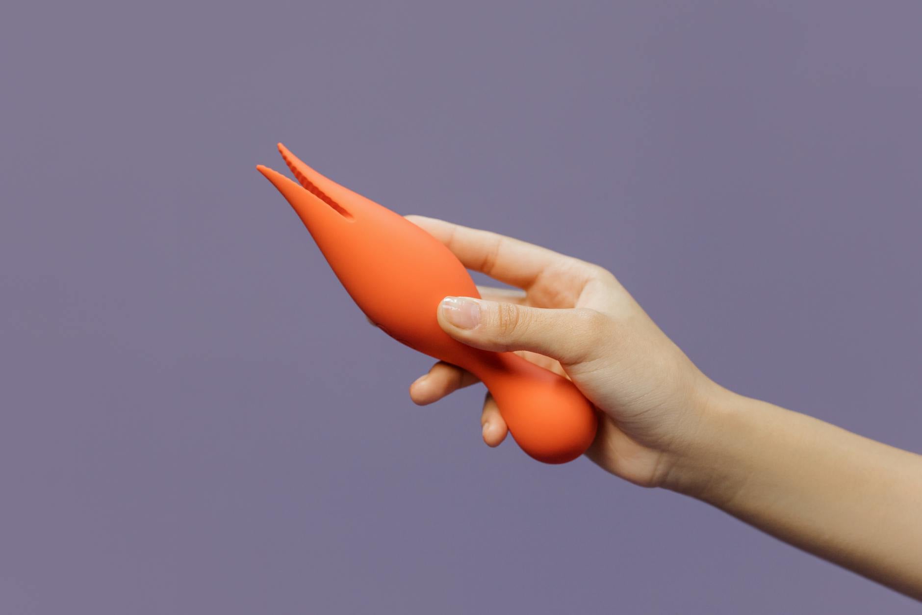 A hand holding a lemon vibrator against a minimalistic backdrop, showcasing modern sexual wellness.