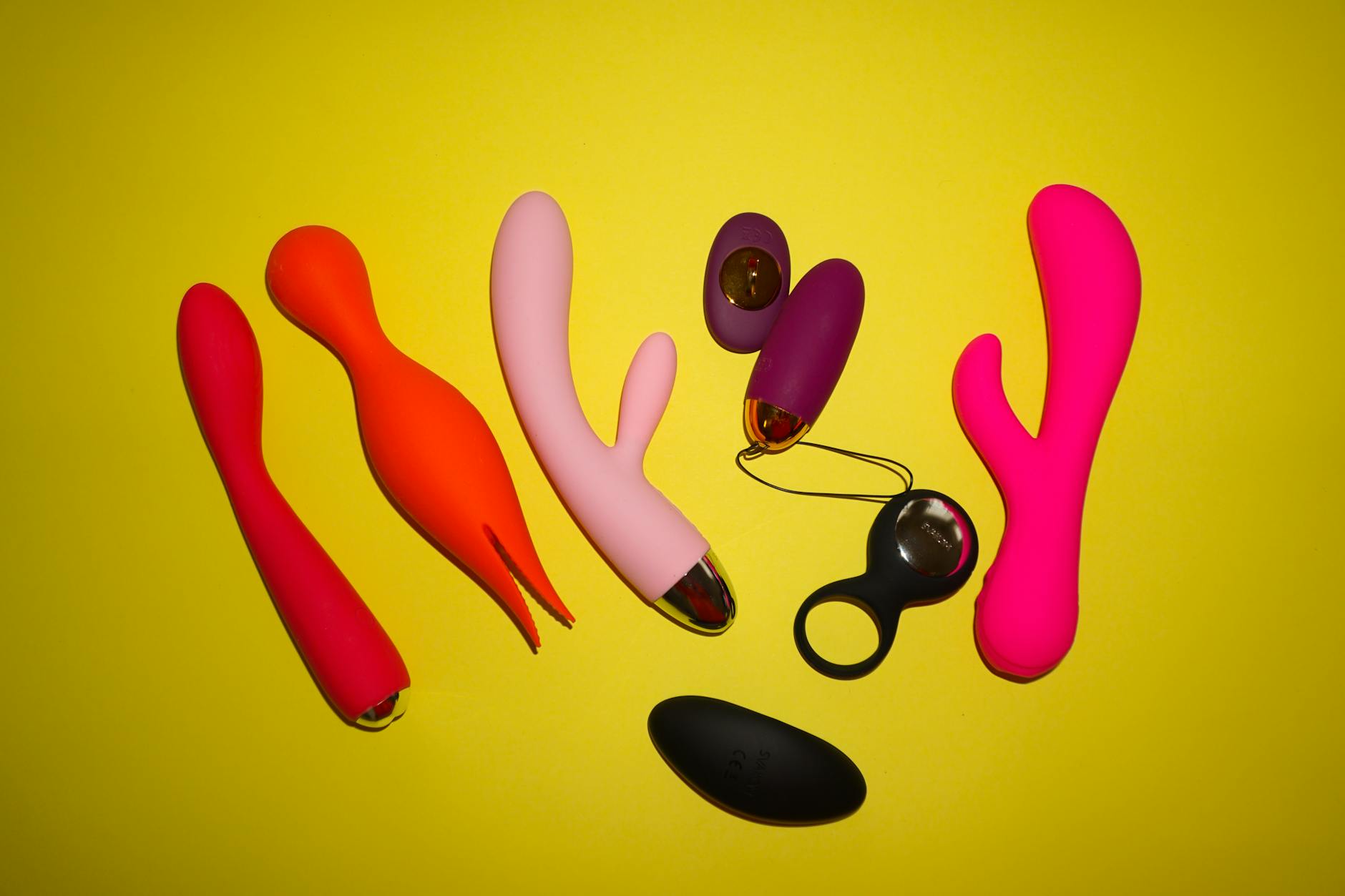 Hand holding a blue silicone clitoral vibrator against a purple background, representing self-pleasure and sexual wellness