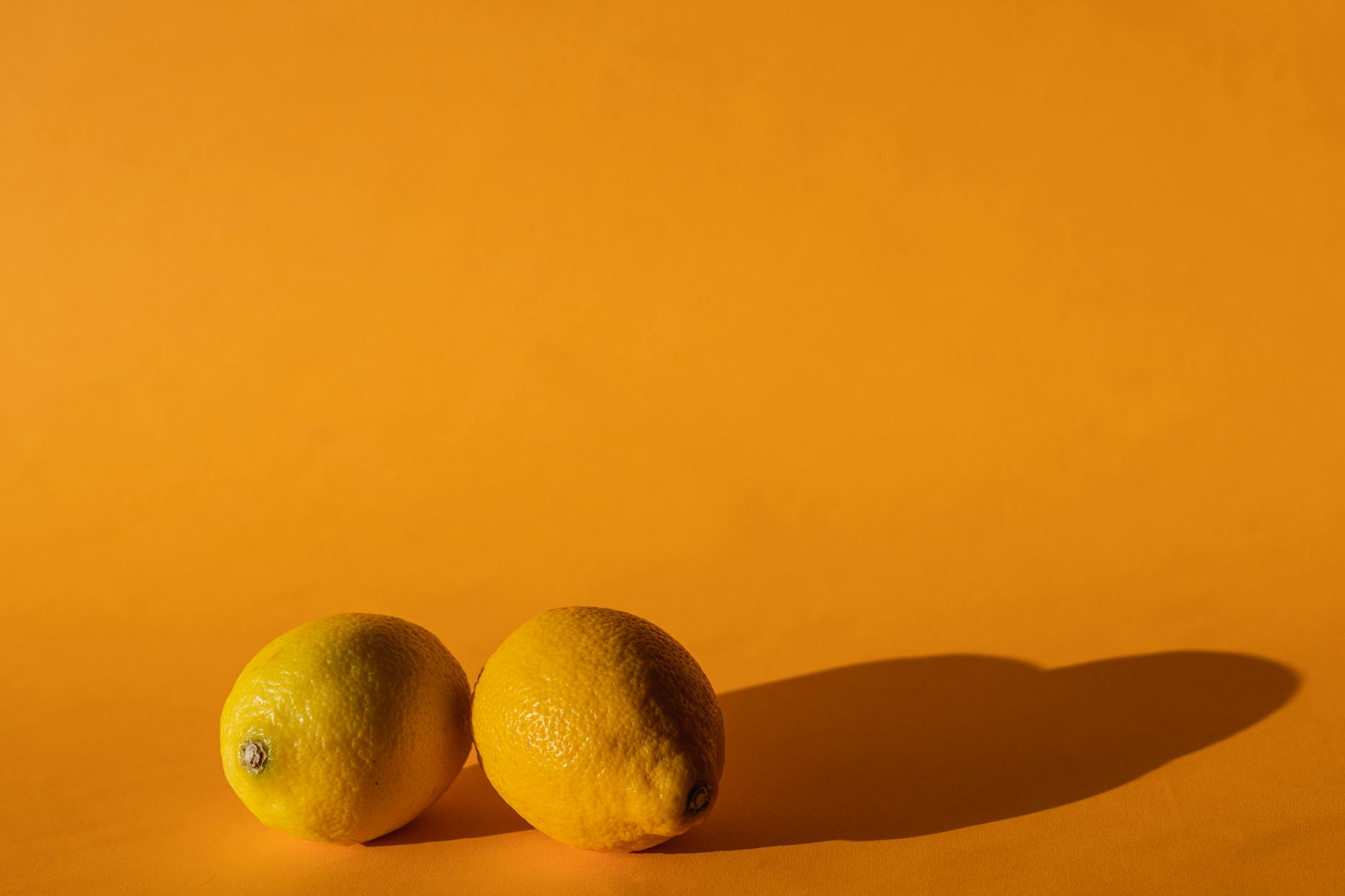 Fresh lemons arranged on a bright yellow background, symbolizing the natural changes of aging and sexual wellness